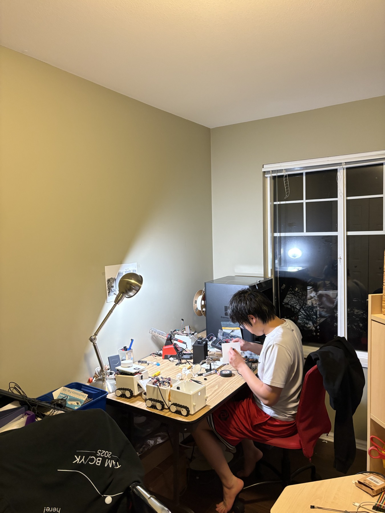 Christopher working at a desk with swarm robot prototypes and electronics parts.