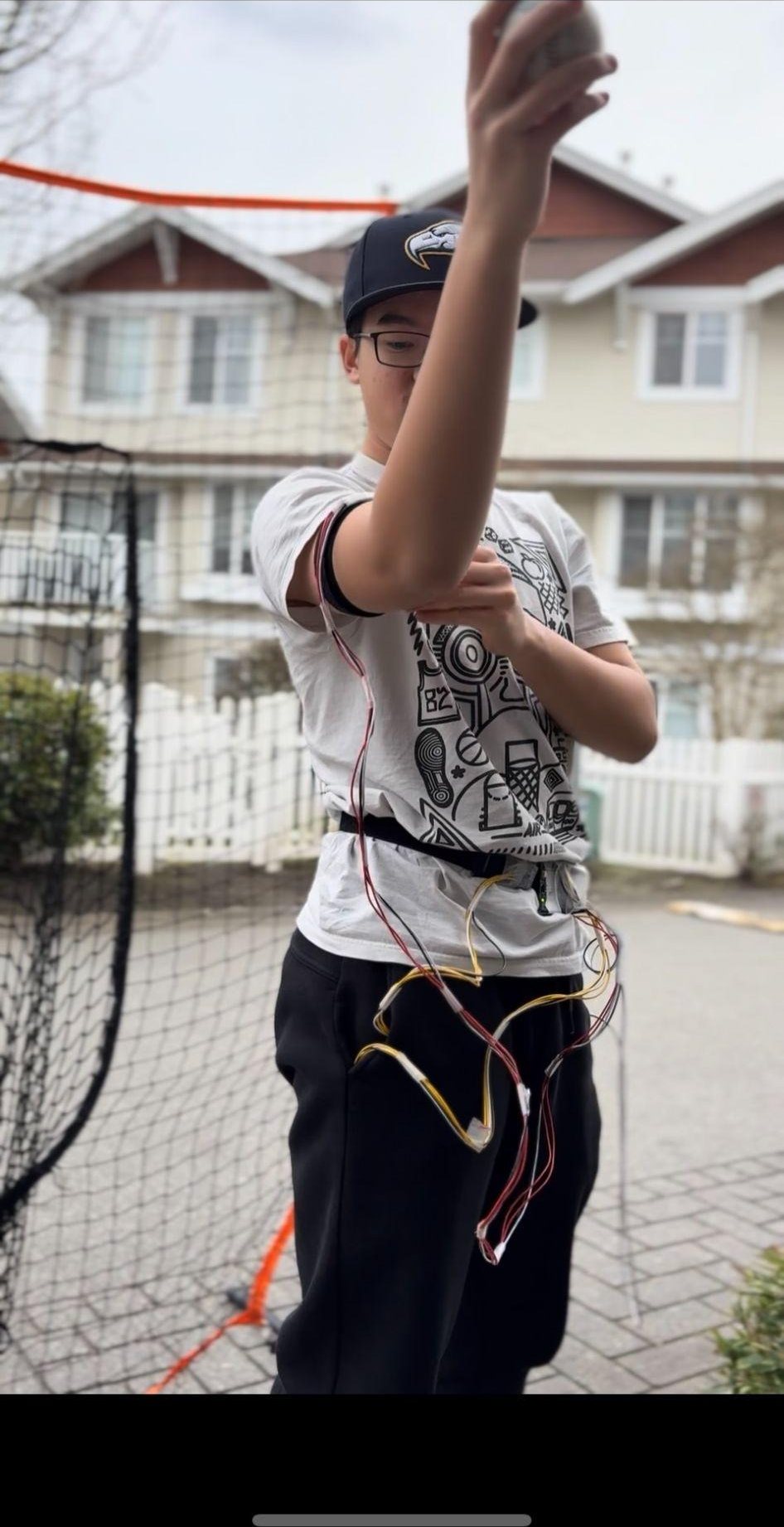 Christopher wearing wired motion sensors while holding a baseball during throwing-data collection.